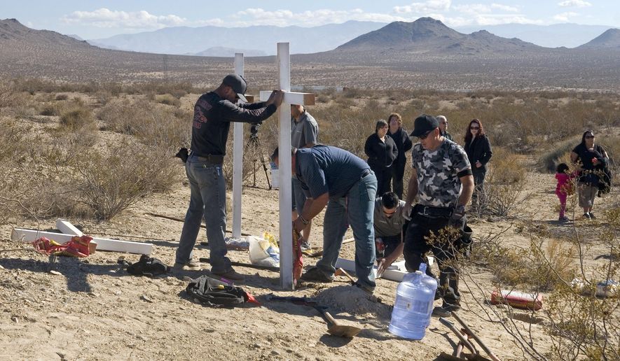 FILE - In this Nov. 20, 2013, file photo, residents of Victorville, Calif., and surrounding communities place crosses near the graves where the McStay family was found in Victorville, Calif. Prosecutors are expected to reveal Tuesday, May 19, 2015, the evidence that led them to Charles "Chase" Merritt, the sole suspect in the case, at a preliminary hearing. A judge previously denied a media request to unseal investigative filings and authorities have said little about the murders of Joseph McStay, 40, his wife, Summer, 43, and their sons, 4-year-old Gianni and 3-year-old Joseph Jr. (James Quigg/The Victor Valley Daily Press via AP, File)
