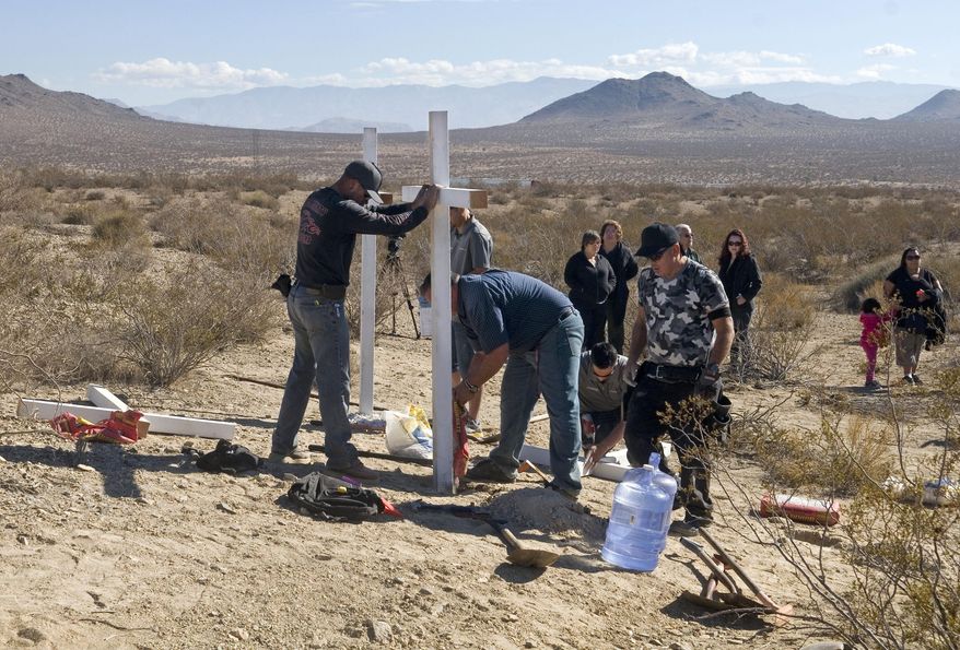 FILE - In this Nov. 20, 2013, file photo, residents of Victorville, Calif., and surrounding communities place crosses near the graves where the McStay family was found in Victorville, Calif. Prosecutors are expected to reveal Tuesday, May 19, 2015, the evidence that led them to Charles "Chase" Merritt, the sole suspect in the case, at a preliminary hearing. A judge previously denied a media request to unseal investigative filings and authorities have said little about the murders of Joseph McStay, 40, his wife, Summer, 43, and their sons, 4-year-old Gianni and 3-year-old Joseph Jr. (James Quigg/The Victor Valley Daily Press via AP, File)
