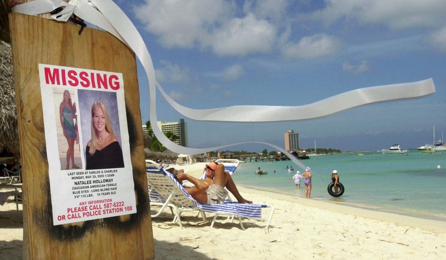 FILE - This June 10, 2005 file photo shows a missing poster for Natalee Holloway, a high school graduate of Mountain Brook, Alabama who disappeared while on a graduation trip to Aruba on May 30, 2005, on Palm Beach where tourists sunbathe in Aruba. Aruba prosecutors said Wednesday, May 20, 2015 a tip about the potential location of Holloway's body turned out to be false after spending weeks investigating the claim in the unsolved, decade-long disappearance of the U.S. teen. (AP Photo/Leslie Mazoch, File)
