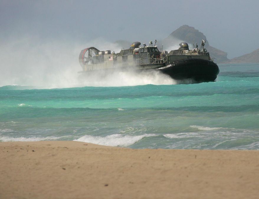 A U.S. Navy Landing Craft Air Cushion (LCAC) amphibious vehicle rushes the beach at Bellows Air Force Station on Oahu, Hawaii during joint amphibious exercises, as the U.S. Marine Corps and Navy host defense leaders from around the Pacific, Tuesday, May 19, 2015. The first-of-its kind meeting comes as territorial disputes over islands are growing more heated in the region. (AP Photo/Caleb Jones)