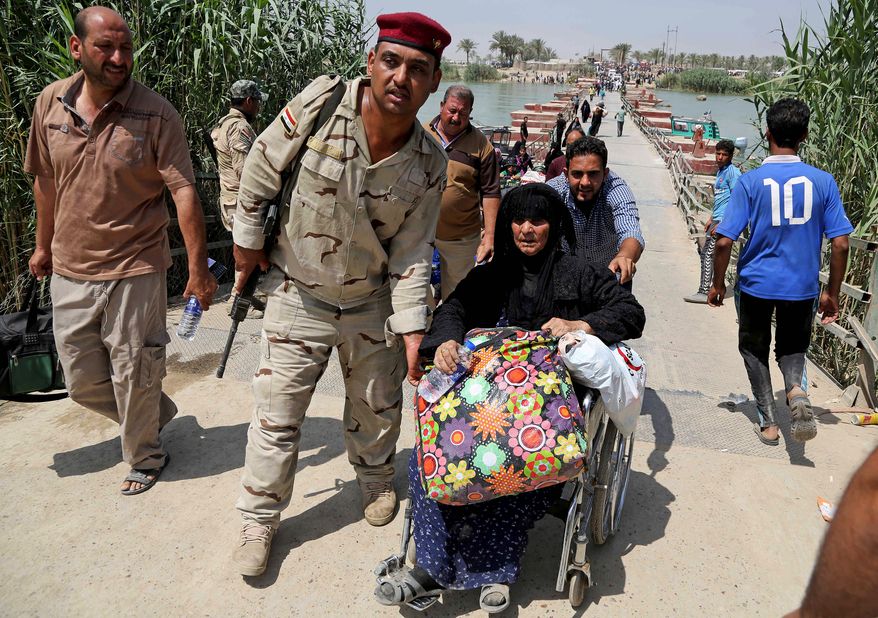 An Iraqi soldier helped one of thousands of Ramadi residents leave Wednesday after the city was seized by Islamic State fighters. Former trainers say Iraqi troops are in dire need of unity and leadership in government. (Associated Press)