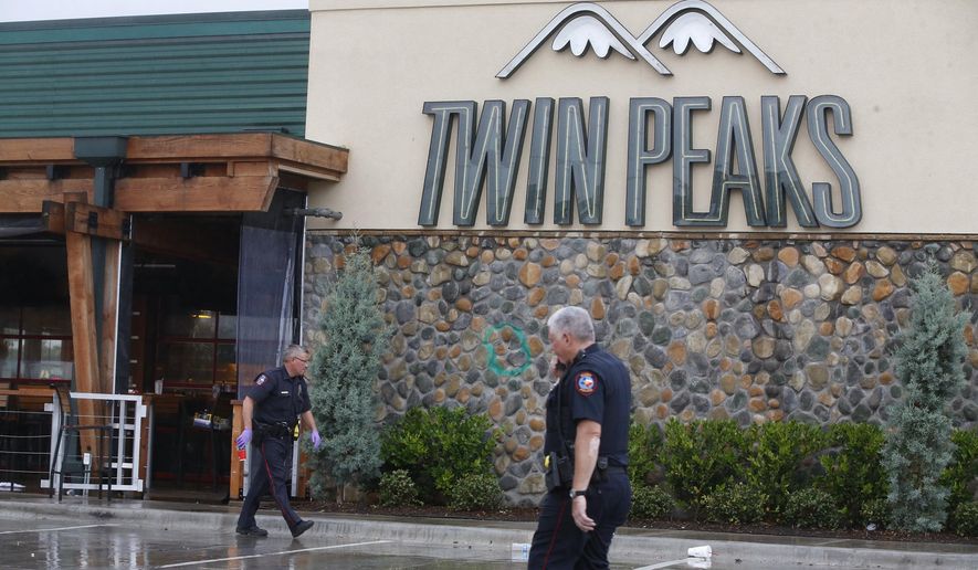 Waco police officers walk along the perimeter of Twin Peaks restaurant during an investigation Wednesday, May 20, 2015 in Waco, Texas. A deadly weekend shootout involving rival motorcycle gangs apparently began with a parking dispute and someone running over a gang member's foot, police said Tuesday. (Rod Aydelotte/Waco Tribune Herald, via AP)