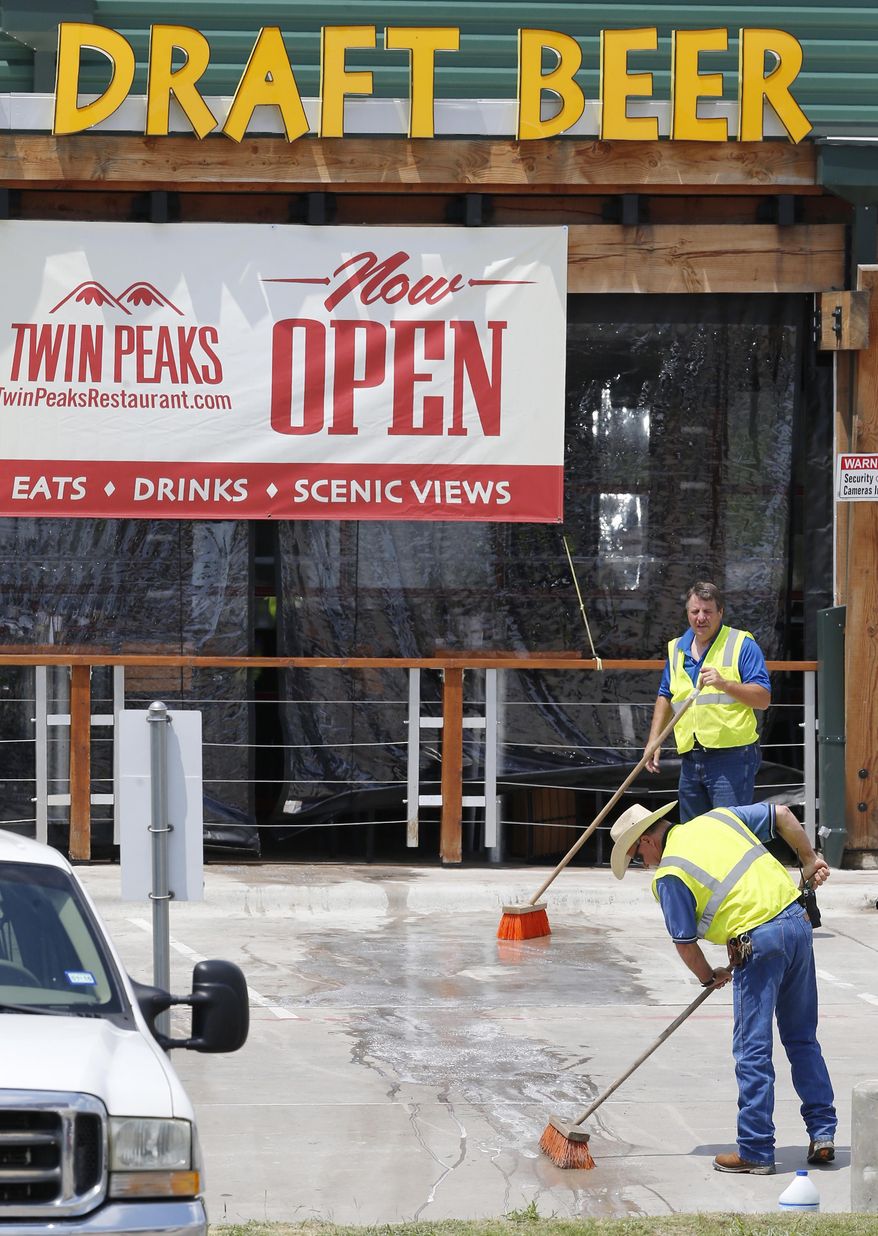 Workers clean the side entrance of the Twin Peaks restaurant, Wednesday, May 20, 2015, in Waco, Texas, as local businesses reopened after a deadly shootout involving rival motorcycle gangs that unfolded last weekend at the restaurant. (Rod Aydelotte/Waco Tribune Herald, via AP)