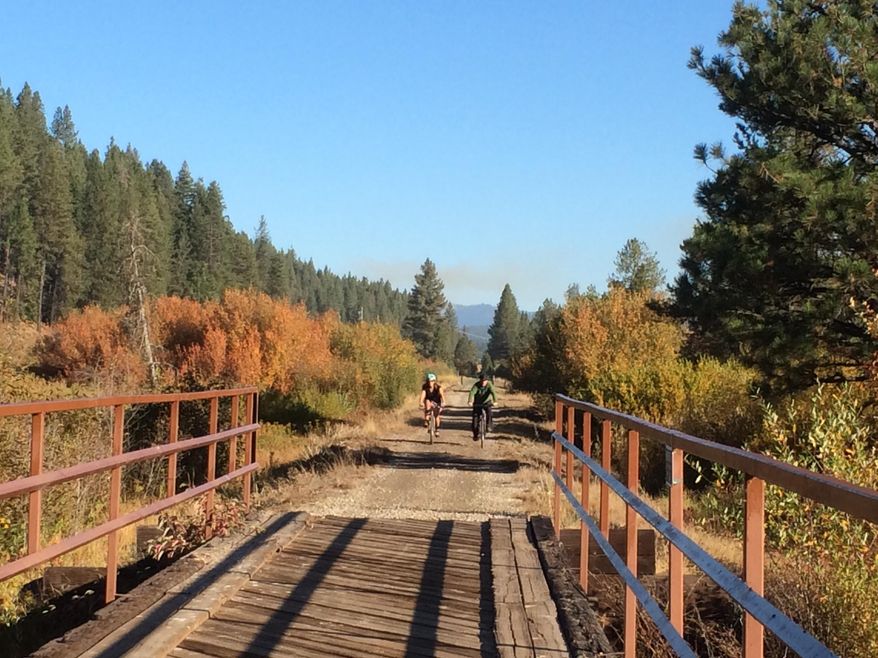 This September 2014 photo provided by Anne Wallace Allen shows her and her husband Eric Allen on one of many bicycle bridges on the Weiser River Trail in central Idaho. The trail is a converted rail bed that runs 85 miles between two small towns in one of the state’s most beautiful areas. (Anne Wallace Allen via AP)