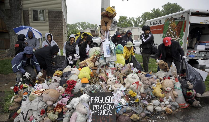 Volunteers remove items left at a makeshift memorial for Michael Brown Wednesday, May 20, 2015, in Ferguson, Mo. The memorial that has marked the place where Brown was fatally shot by a police officer in August has been removed and will be replaced with a permanent plaque, Ferguson's Mayor James Knowles said Wednesday. (AP Photo/Jeff Roberson)