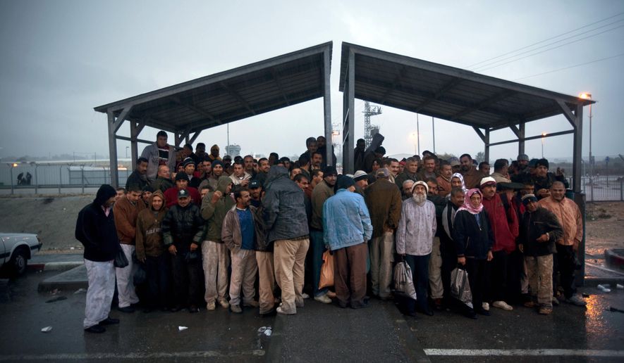 File - In this Nov. 3, 2009 file photo, Palestinian workers stand under a shelter to keep dry from the rain as they wait for transportation after crossing from the West Bank town of Qalqilya to work in Israel, at the Israeli army's checkpoint near Kibbutz Eyal in central Israel. Israeli Prime Minister Benjamin Netanyahu on Wednesday, May 20, 2015, called off a proposed plan to segregate Palestinians from Israelis on West Bank buses, overruling his defense minister amid a flurry of criticism in an attempt to avert the first crisis of his new government. (AP Photo/Oded Balilty, File)