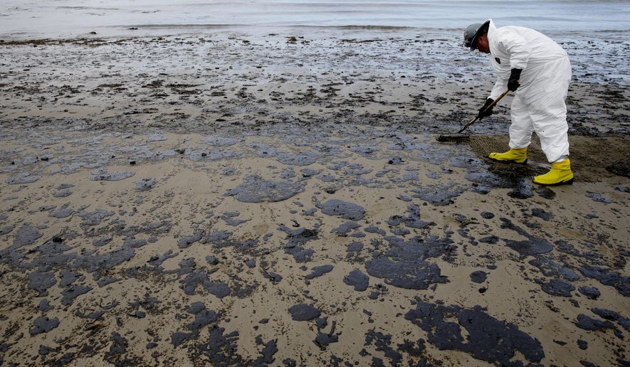 A worker removes oil from the beach at Refugio State Beach, north of Goleta, Calif., Thursday, May 21, 2015. More than 7,700 gallons of oil has been raked, skimmed and vacuumed from a spill that stretched across 9 miles of California coast, just a fraction of the sticky, stinking goo that escaped from a broken pipeline, officials said. (AP Photo/Jae C. Hong)
