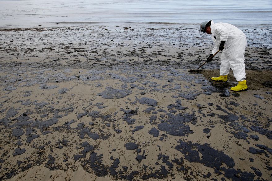 A worker removes oil from the beach at Refugio State Beach, north of Goleta, Calif., Thursday, May 21, 2015. More than 7,700 gallons of oil has been raked, skimmed and vacuumed from a spill that stretched across 9 miles of California coast, just a fraction of the sticky, stinking goo that escaped from a broken pipeline, officials said. (AP Photo/Jae C. Hong)