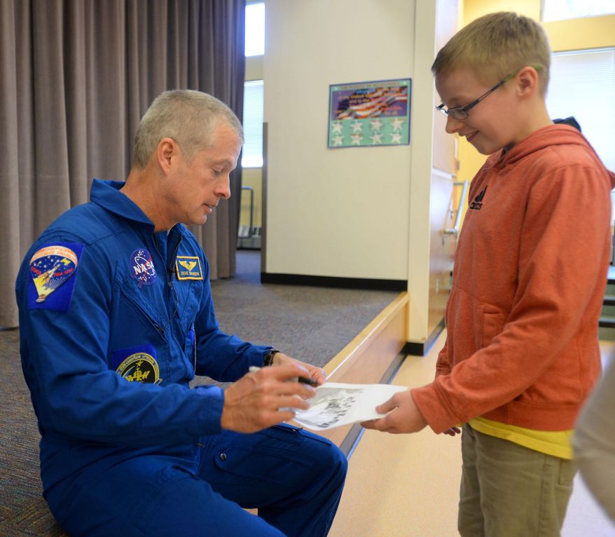 ADVANCE FOR SUNDAY, MAY 24 - In this photo taken May 6, 2015, Astronaut Steve Swanson signs his autograph for Fawn Mountain Elementary School sixth-grader John Call in Ketchikan, Alaska. Swanson visited the school as part of American300’s tour of Alaska. American300 is an all-volunteer, nonprofit organization that brings interesting and relevant guests to U.S. service stations around the world. (Taylor Balkom/Ketchikan Daily News via the AP)