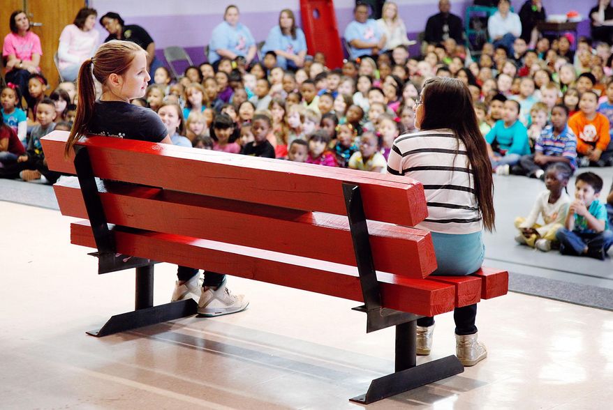 ADVANCED FOR RELEASE TUESDAY, MAY 26, 2015 Madison Ayscue, left, and Cristesbey Picaz simulate how the new Buddy Bench is to be used by students at the school. (Mark Dolejs/The Daily Dispatch via AP)