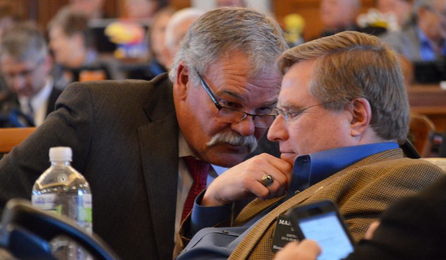 Rep. John Barker, R-Abilene, left, and Rep. Mark Hutton, R-Wichita, right, huddle during the House's session, Thursday, May 21, 2015, at the Statehouse in Topeka, Kan. The House has approved a bill to move city and local school board elections from the spring to the fall of odd-numbered years. (AP Photo/Nicholas Clayton)