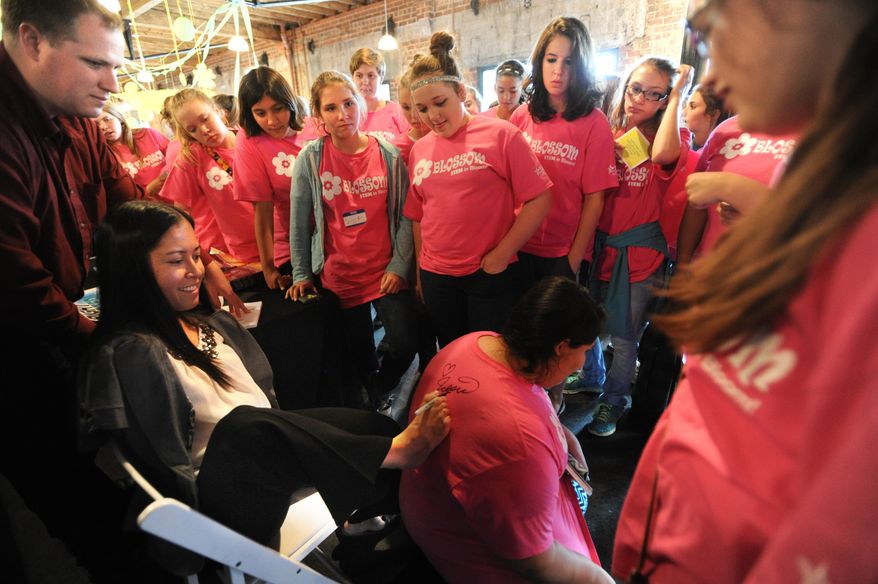 ADVANCE FOR USE MONDAY, MAY 25 - In this photo taken Tuesday, May 19, 2015, pilot Jessica Cox signs T-shirts after speaking to Texas State Technical College’s Blossom Day Camp in Abilene, Texas. Cox, born without arms, is the first person in aviation history to fly a plane with only her feet. (Nellie Doneva/The Abilene Reporter-News via AP)