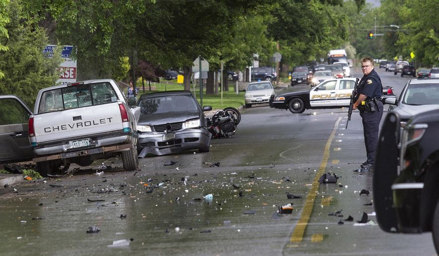 In a Tuesday, May 19, 2015 photo, a Grand Junction police officer guards the scene at 8th Street and Grand Avenue after an accident in which one man died and two vehicles and a motorcycle were wrecked on May 19, 2015, in Grand Junction, Colo. According to a report release by the police department, Preston Ellis, 57, of Grand Junction was killed when the motorcycle on which he was riding was struck by a pickup truck driven by David Gaines, 17, also of Grand Junction. Gaines left the scene on foot with a rifle and a few minutes later attempted to carjack a Toyota SUV with a woman and her two children inside at a nearby park. Gaines was shot by Grand Junction police officer Martin Donohue during the carjacking attempt. Gaines later died at St. Mary's Hospital. (Dean Humphrey/The Grand Junction Daily Sentinel via AP) MANDATORY CREDIT