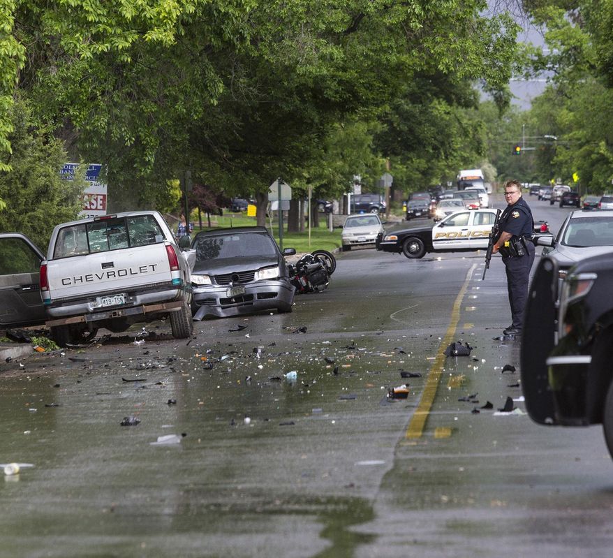In a Tuesday, May 19, 2015 photo, a Grand Junction police officer guards the scene at 8th Street and Grand Avenue after an accident in which one man died and two vehicles and a motorcycle were wrecked on May 19, 2015, in Grand Junction, Colo. According to a report release by the police department, Preston Ellis, 57, of Grand Junction was killed when the motorcycle on which he was riding was struck by a pickup truck driven by David Gaines, 17, also of Grand Junction. Gaines left the scene on foot with a rifle and a few minutes later attempted to carjack a Toyota SUV with a woman and her two children inside at a nearby park. Gaines was shot by Grand Junction police officer Martin Donohue during the carjacking attempt. Gaines later died at St. Mary's Hospital. (Dean Humphrey/The Grand Junction Daily Sentinel via AP) MANDATORY CREDIT