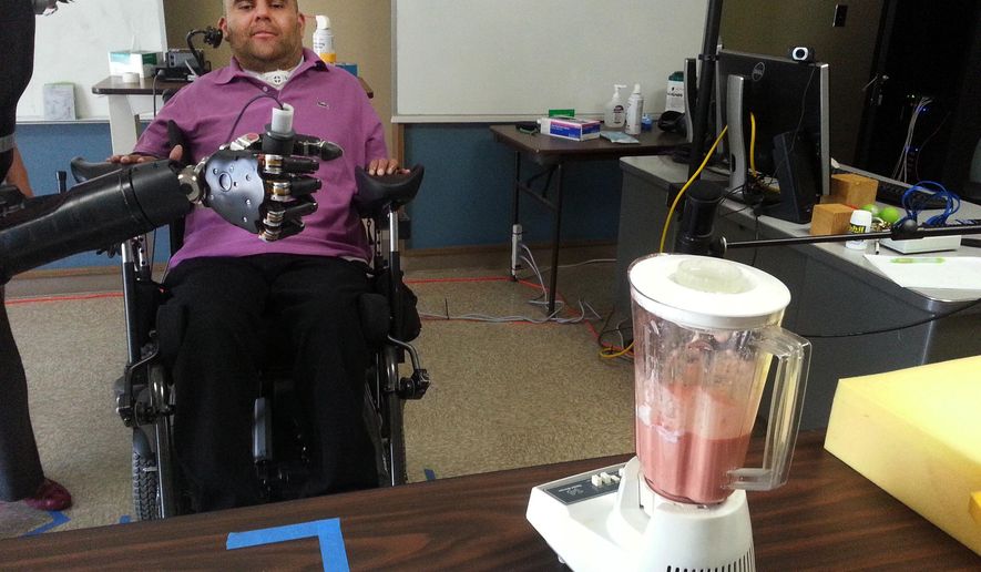 In this March 28, 2014 photo provided by the California Institute of Technology, Erik Sorto uses his mind to control a robotic arm to make a smoothie in Pasadena, Calif. Two years earlier, doctors in California implanted a pair of tiny chips in his brain that decoded his thoughts to move the free-standing robotic arm. The 34-year-old has been working with researchers and occupational therapists to practice and fine-tune his movements. (Spencer Kellis/Caltech via AP)