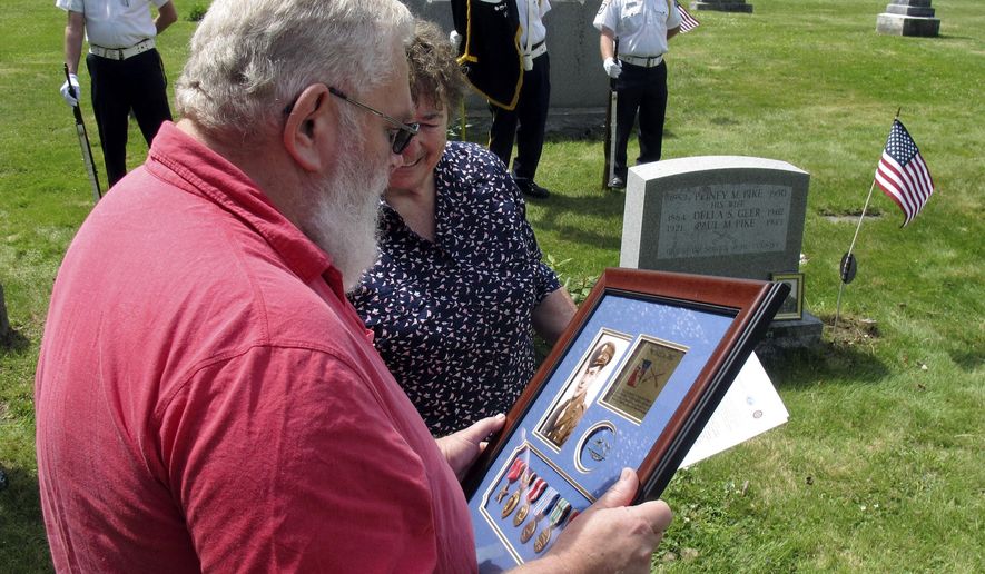 Paul Pike, left, of Roxbury, Vt., looks at a Purple Heart and other medals earned by his father's cousin, also named Paul Pike, who was killed during World War II, that he was presented on Thursday, May 21, 2015, in Worcester, Vt. Audrey Richardson, partially hidden, of the Worcester Historical Society, watches during a ceremony arranged by the society and the organization Purple Hearts Reunited. (AP Photo/Wilson Ring)