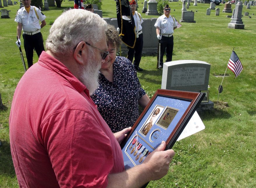 Paul Pike, left, of Roxbury, Vt., looks at a Purple Heart and other medals earned by his father's cousin, also named Paul Pike, who was killed during World War II, that he was presented on Thursday, May 21, 2015, in Worcester, Vt. Audrey Richardson, partially hidden, of the Worcester Historical Society, watches during a ceremony arranged by the society and the organization Purple Hearts Reunited. (AP Photo/Wilson Ring)