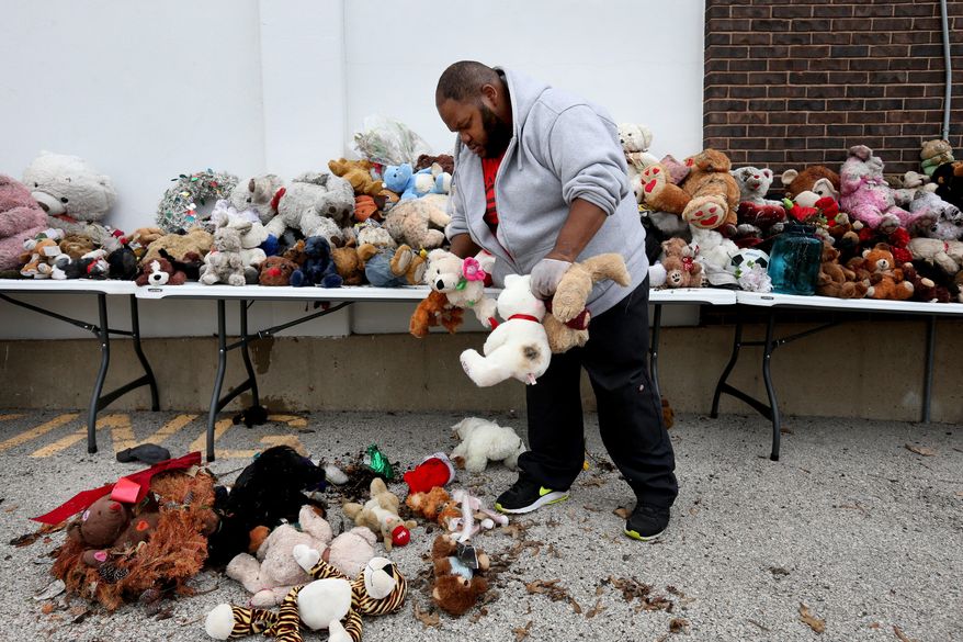 Marcus Allen shakes out water and debris from stuffed animals that were collected from the Michael Brown memorial in Ferguson, Mo., Thursday, May 21, 2015. A plaque and metallic likeness of a dove have been installed in Michael Brown's memory near the spot where the unarmed, black 18-year-old was shot and killed last summer by a white Ferguson police officer. The plaque was installed a day after the mid-street memorial for Brown was cleared. (David Carson/St. Louis Post-Dispatch via AP) EDWARDSVILLE INTELLIGENCER OUT; THE ALTON TELEGRAPH OUT; MANDATORY CREDIT