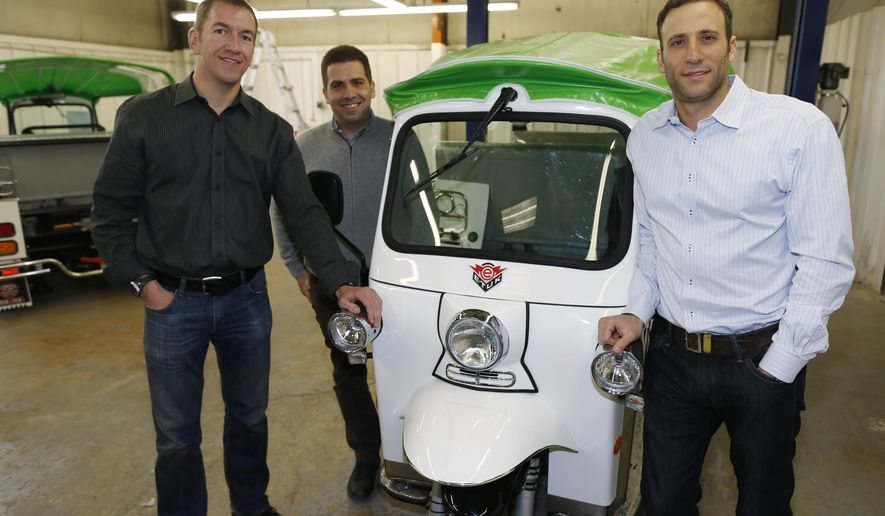 In this photograph taken Friday, Feb. 27, 2015, Colin Sommers, left, director of engineering for eTuk USA, Walid Mourtada, center, chief executive officer, and Michael Fox show off one of their company's electric Tuk-Tuk models being prepared for delivery at the trio's manufacturing plant in northeast Denver. It's too soon to know if Americans will embrace tuk-tuks, but Fox, director of sales and marketing for eTuk USA, says the company has been selling the vehicles across the country to individuals, marketing companies and food vendors for between $16,950 and $25,000, depending on how they are customized. (AP Photo/David Zalubowski)