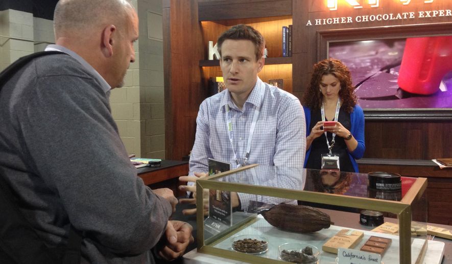 ADVANCE FOR USE SUNDAY, MAY 24, AND THEREAFTER - In this Wednesday, May 20, 2015, photo, Kiva Confections CEO Scott Palmer, center, talks to a potential client at a marijuana trade show at the Marijuana Business Conference & Expo in Chicago. The California company makes premium chocolates infused with cannabis. (AP Photo/Carla K. Johnson)