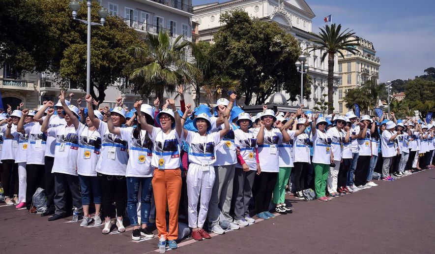 FILE - In this May 8, 2015 file photo, employees of the Tiens Group, a Chinese company which sells medicinal products, including via direct marketing, cheer as they attend a parade organized by CEO Li Jinyuan as part of a four-day celebration weekend for the 20th anniversary of his company, on the Promenade des Anglais, Nice, southeastern France. All-expenses-paid trips to reward top earners aren’t unusual, but Chinese direct-sales companies are taking it to an extreme by sending thousands abroad on the same package tour. (AP Photo/Lionel Cironneau, File)