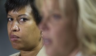 Washington Mayor Muriel Bowser listens at left as Police Chief Cathy Lanier speaks during a news conference in Washington, Thursday, May 21, 2015, to discuss the investigation into the mysterious slayings of a wealthy Washington family and their housekeeper. Lanier said investigators believe a suspect in the slayings is in the Brooklyn area of New York City.  (AP Photo/Cliff Owen)