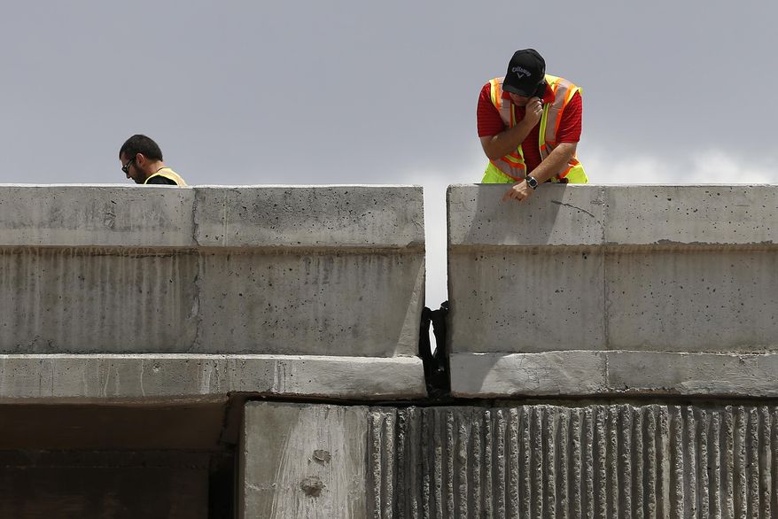 Workers inspect damage to a freeway ramp Friday, May 22, 2015, in Las Vegas. The ramp leading to Interstate 15 was closed from damage after an earthquake that struck a rural area of southern Nevada. (AP Photo/John Locher)