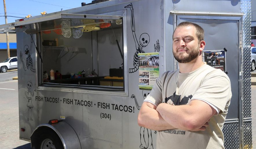 ADVANCE FOR SUNDAY MAY 24 AND THEREAFTER - In a Wednesday May 13, 2015 photo, Poncho & Lefty's owner Joel Sullivan poses with his food truck on Prince St. in Beckley, W.Va. Sullivan recently started the food truck, selling fish, chicken tacos downtown and at regionally events. (Chris Jackson/The Register-Herald via AP)