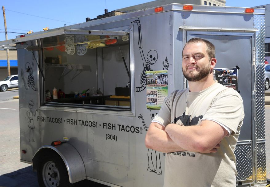 ADVANCE FOR SUNDAY MAY 24 AND THEREAFTER - In a Wednesday May 13, 2015 photo, Poncho & Lefty's owner Joel Sullivan poses with his food truck on Prince St. in Beckley, W.Va. Sullivan recently started the food truck, selling fish, chicken tacos downtown and at regionally events. (Chris Jackson/The Register-Herald via AP)