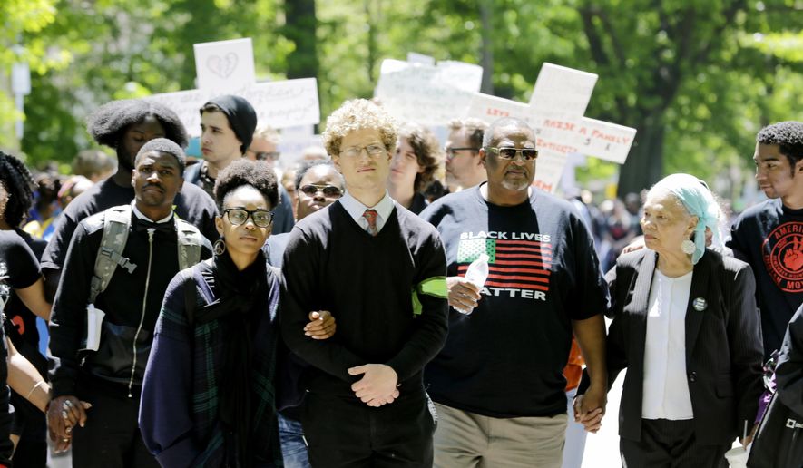 Protesters link arms and hands as they walk near where the county prosecutor lives in Cleveland on Saturday, May 23, 2015. Michael Brelo, a white Cleveland patrolman who fired down through the windshield of the car of Timothy Russell, a black suspect, at the end of a 137-shot barrage by police that left the two unarmed black occupants dead was acquitted Saturday of criminal charges by a judge who said he could not determine Brelo alone fired the fatal shots. (AP Photo/Tony Dejak)