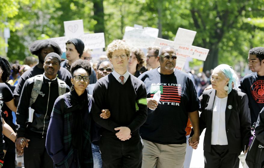 Protesters link arms and hands as they walk near where the county prosecutor lives in Cleveland on Saturday, May 23, 2015. Michael Brelo, a white Cleveland patrolman who fired down through the windshield of the car of Timothy Russell, a black suspect, at the end of a 137-shot barrage by police that left the two unarmed black occupants dead was acquitted Saturday of criminal charges by a judge who said he could not determine Brelo alone fired the fatal shots. (AP Photo/Tony Dejak)