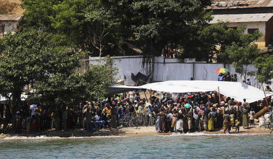 Refugees who fled Burundi's violence and political tension watch others leave on a ship freighted by the UN , at Kagunga on Lake Tanganyika, Tanzania, Saturday, May 23, 2015 to be taken to the port city of Kigoma. An outbreak of cholera has infected 3,000 people in a Tanzanian border region where refugees fleeing political unrest in Burundi have massed, the U.N. Refugee Agency said Friday, May 22, 2015. Some 300 to 400 new cases of cholera are being reported daily. At least 31 people — 29 refugees and two Tanzanians — already have died of the disease, according to UNHCR. More than 64,000 Burundians have fled to Tanzania in recent weeks, UNHCR said, escaping the unrest sparked by their president's bid for a third term that many say is unconstitutional. (AP Photo/Jerome Delay)