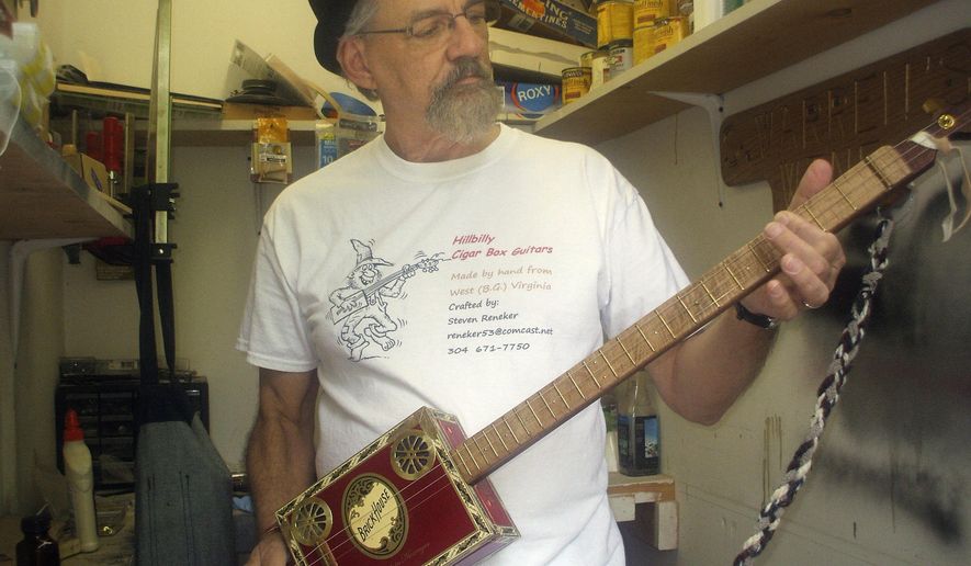 ADVANCE FOR SUNDAY MAY 24 AND THEREAFTER This Sunday May 17, 2015 photo shows artisan Steve Reneker, owner of Hillbilly Cigar Box Guitars, plays the special one he handcrafted to be raffled off as a fundraiser for the Berkeley County BackPack Program in Hedgesville, W.Va.  (Jenni Vincent/The Journal via AP)
