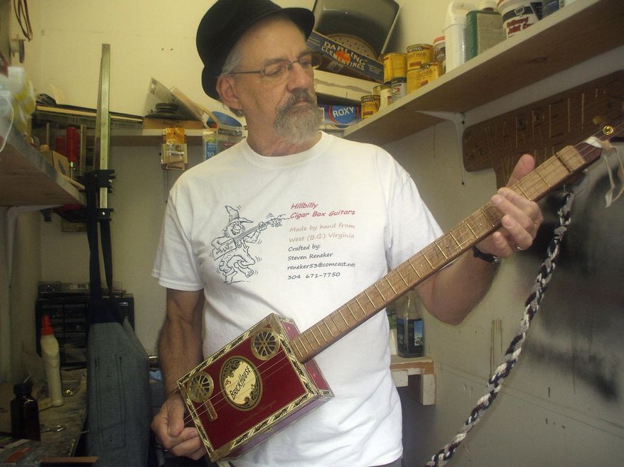 ADVANCE FOR SUNDAY MAY 24 AND THEREAFTER This Sunday May 17, 2015 photo shows artisan Steve Reneker, owner of Hillbilly Cigar Box Guitars, plays the special one he handcrafted to be raffled off as a fundraiser for the Berkeley County BackPack Program in Hedgesville, W.Va. (Jenni Vincent/The Journal via AP)