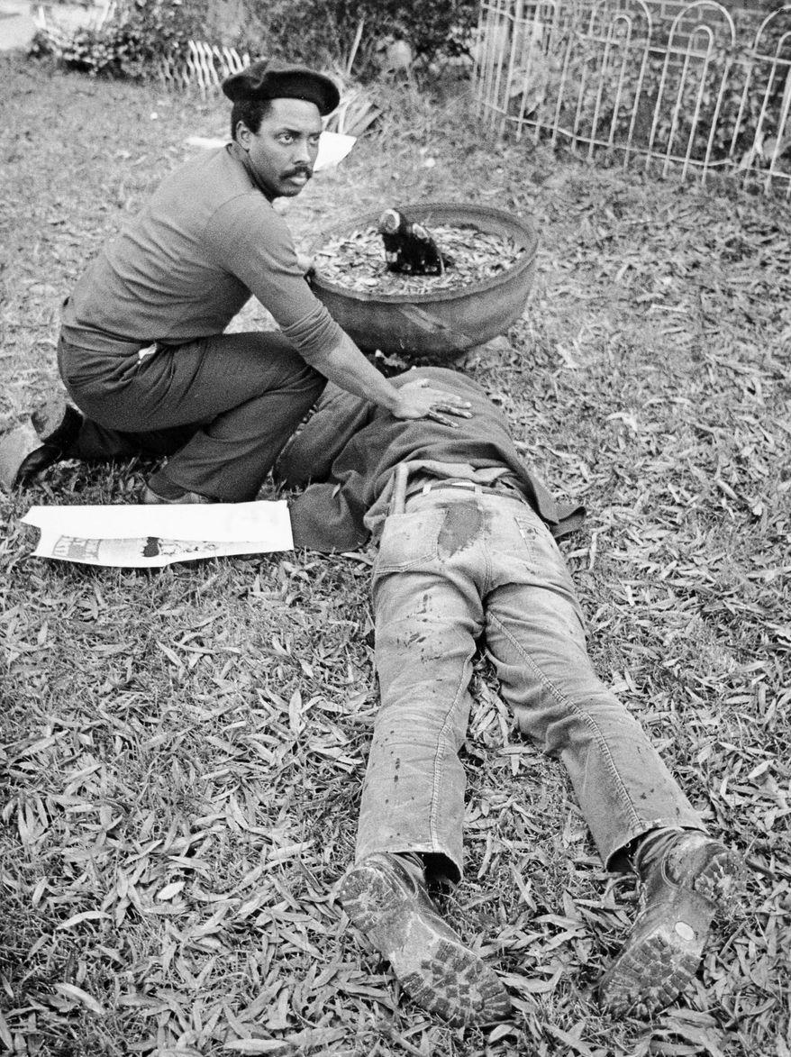 FILE - In this Nov. 3, 1979 file photo, Workers Viewpoint Organization member Nelson Johnson kneels by victim in aftermath of shooting in Greensboro, N.C. The state, with the blessing of the Greensboro City Council, will use the word "massacre" for a highway historical marker commemorating the deaths of five Communist Workers Party members during a confrontation with Ku Klux Klansmen and the American Nazi Party. The marker, which will be dedicated Sunday, May 24, 2015. (Jim Stratford /News & Record via AP)