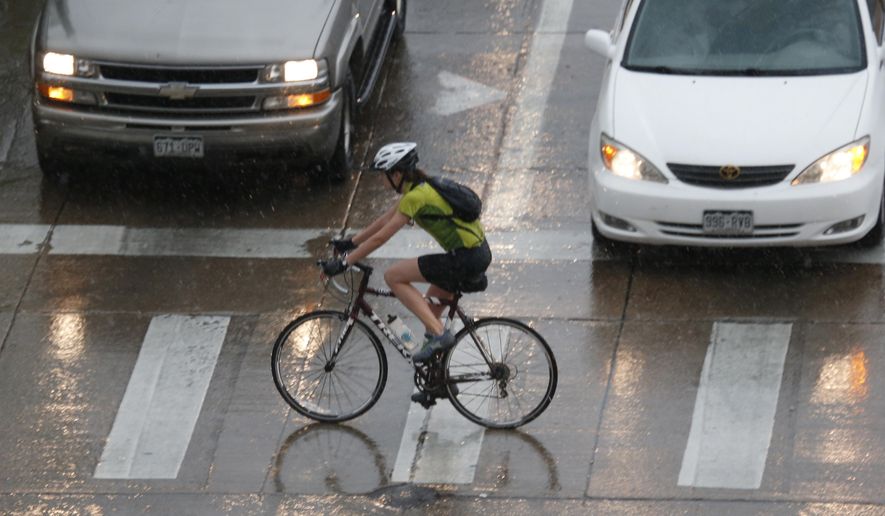 A bicyclist rides through a rainstorm with hail in Denver on Saturday, May 23, 2015. Forecasters predict another rainy day for the Mile High City as another in a series of storms sweeps over the central plains. (AP Photo/David Zalubowski)