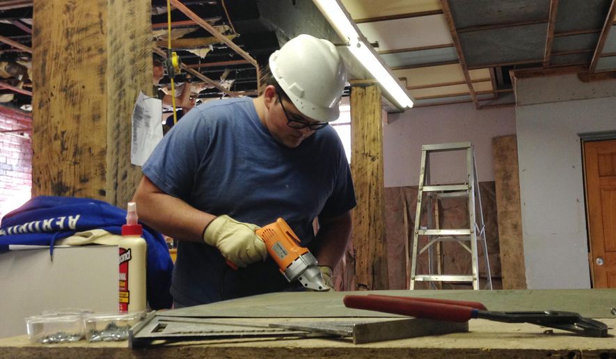 In this March 25, 2015 photo, Nathaniel Blankenship, 19, works to remodel a 1920s-era warehouse into office space in Williamson, W.Va.  Blankenship is a crew member in a job program with Coalfield Development Corporation, a nonprofit organization that’s part of a movement to help redevelop vacant or dilapidated buildings in West Virginia. (AP Photo/Jonathan Drew)