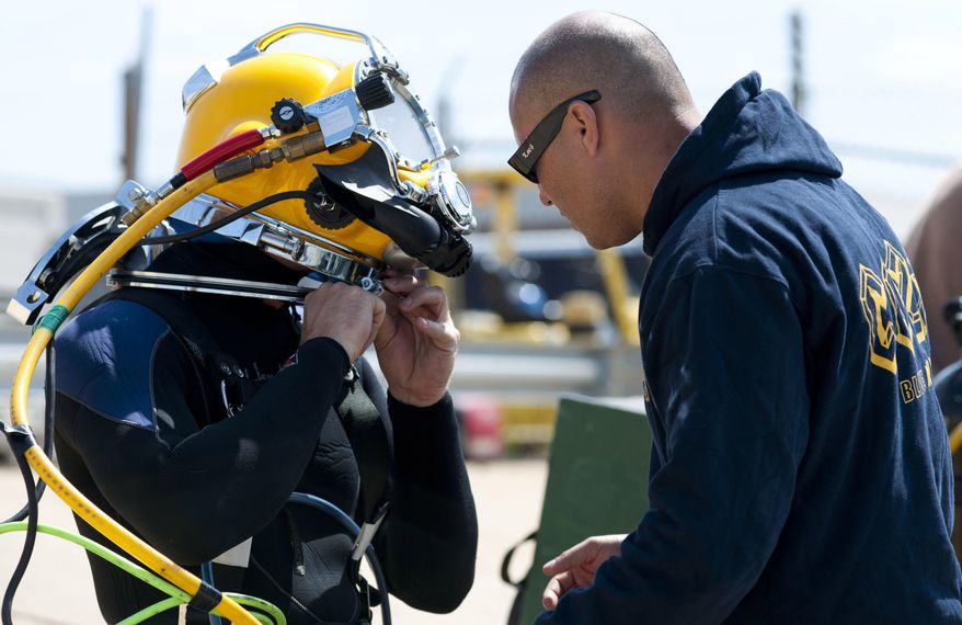 In this Thursday, May 14, 2015 photo provided by the U.S. Navy, Navy diver 1st Class Fernando Almazan, right, assists Navy diver 1st class Travis Arneson, assigned to Mobile Diving Salvage Unit (MDSU) 2, don a Kirby Morgan 37 dive helmet during training at Joint Expeditionary Base Little Creek-Fort Story in Virginia Beach, Va. During this training divers are preparing for an upcoming assignment to salvage of the Civil War ironclad Confederate State Ship (CSS) Georgia in the Savannah Rive in Savannah, Ga. (Petty Officer 2nd class Heather Brown/U.S. Navy via AP)
