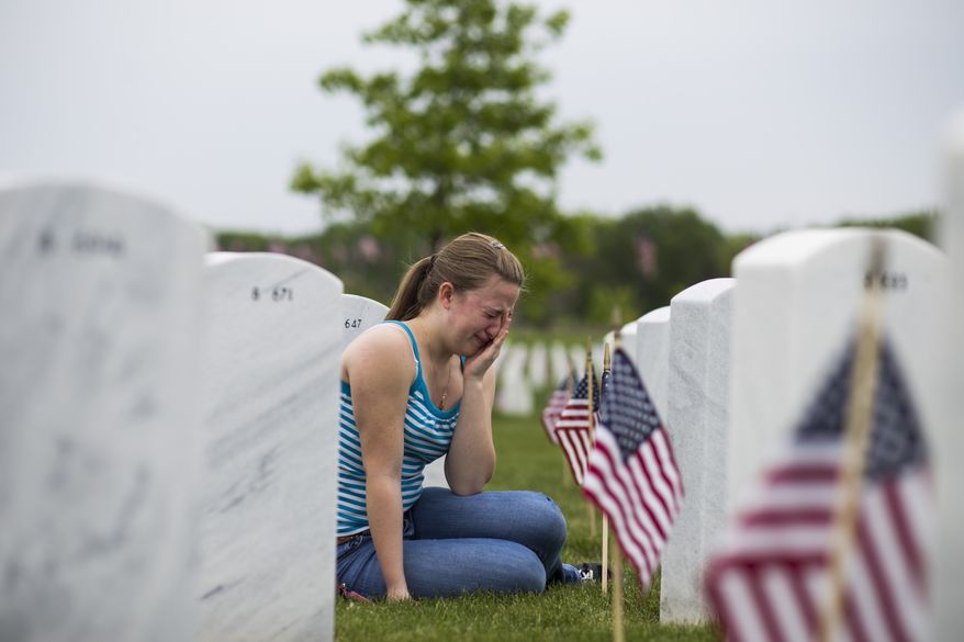 Deandra Christiansen, 16, cries at the gravestone of her father, Eric Christiansen, following a Memorial Day service at the Great Lakes National Cemetery, Sunday, May 24, 2015, in Holly, Mich. Eric served in the National Guard. (Brittany Greeson/The Flint Journal-MLive.com via AP) LOCAL TELEVISION OUT; LOCAL INTERNET OUT