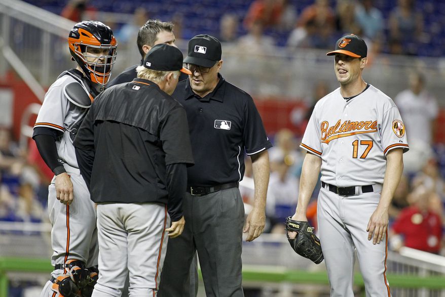 Baltimore Orioles relief pitcher Brian Matusz (17) waits as umpire Paul Emmel, center, speaks with Orioles manager Buck Showalter, as catcher Caleb Joseph stands nearby during the 12th inning of a baseball game in Miami, Saturday, May 23, 2015. Matusz left the game after his forearm was inspected. The Marlins won 1-0. (AP Photo/Joe Skipper)