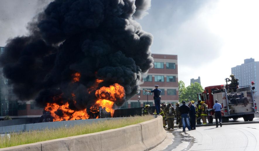 Police and firefighters watch a tanker truck that was carrying 9,000 gallons of unleaded fuel burn after it exploded and caught fire on Interstate 75 in downtown Detroit Sunday, May 24, 2015. The driver wasn't hurt, but Interstate 375 at I-75 remained shut down as well as north I-75 in the area. (AP Photo/Bill Eisner)
