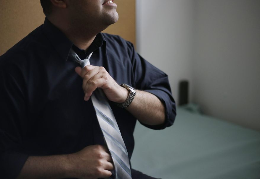 In this Thursday, May 21, 2015 photo, Andres, a 29-year-old serving one year for a deadly DUI crash, adjusts his tie at the Western Massachusetts Correctional Addictions Center in Ludlow, Mass. Prison officials at the center believe dressing for success can help inmates break the stranglehold of addiction. “I have three shirts, three ties," Andres said. “It makes you feel more successful. Or like you’re working toward it, you know?” (AP Photo/Elise Amendola)