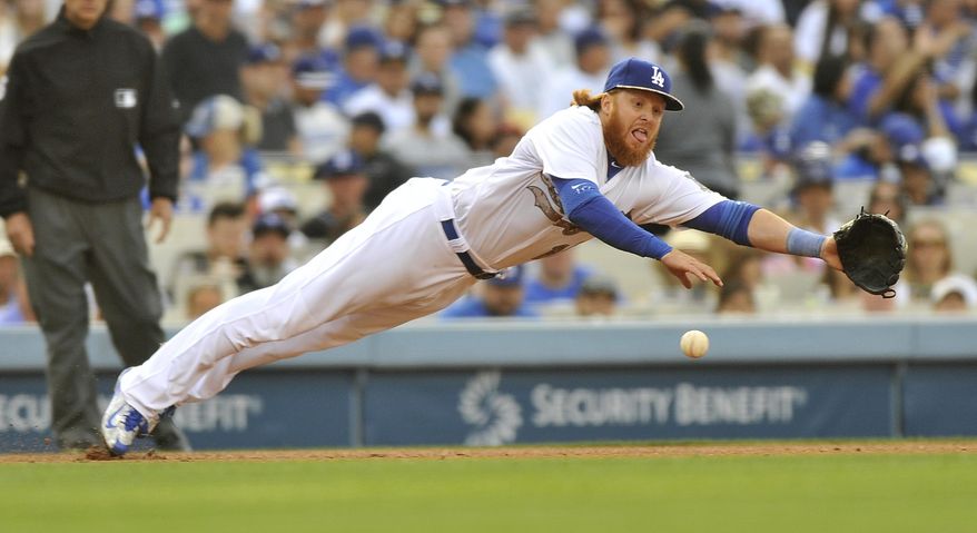 Los Angeles Dodger third baseman Justin Turner dives, but he can't come up with the ball on a single through the infield by Atlanta Braves Jonny Gomes during the fourth inning of a baseball game in Los Angeles, Monday, May 25, 2015. (AP Photo/Richard Hartog)