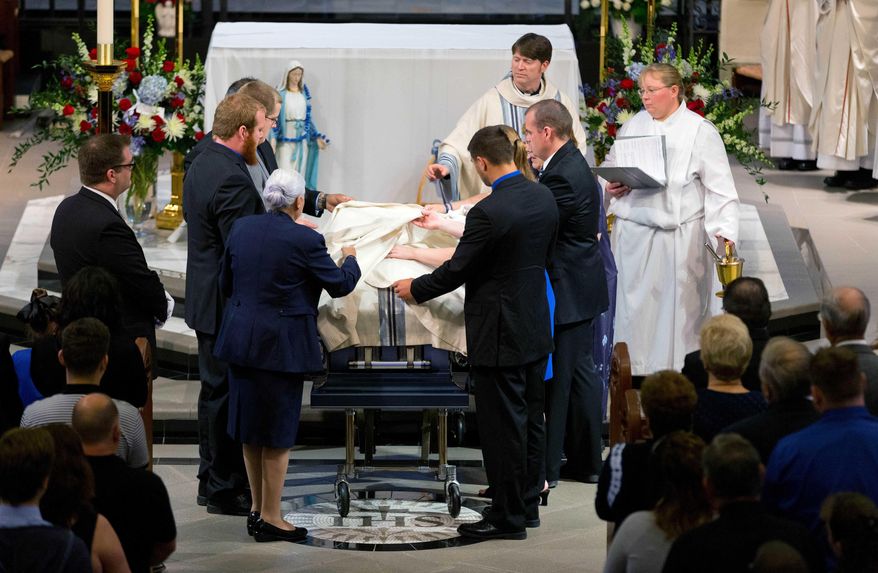 Family members cover the coffin of Omaha police detective Kerrie Orozco during funeral services at St. John's Catholic Church at Creighton University, Tuesday, May 26, 2015 in Omaha, Neb. Orozco was shot to death Wednesday by a fugitive who was fatally wounded by another officer. (Matt Miller/The World-Herald via AP, Pool)