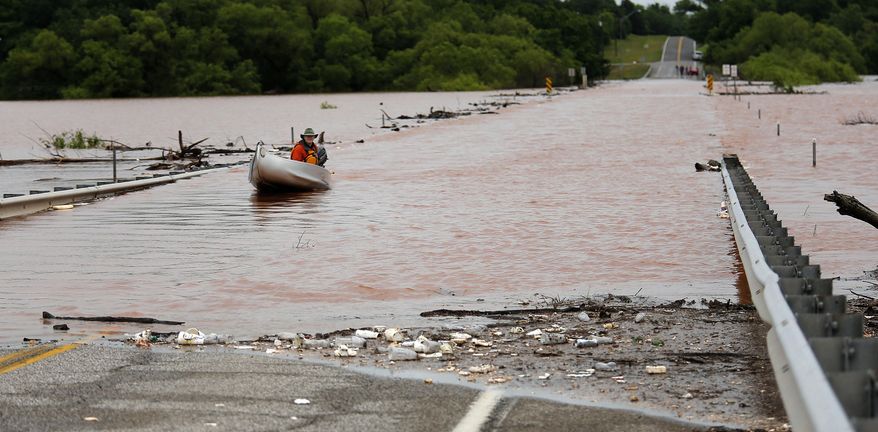 Kevin Young takes a boat on the Alameda bridge over Lake Thunderbird on the Alameda bridge in Norman, Okla., Sunday, May 24, 2015. Young was testing his boat on the flood water to see if he could help a family get across. The family was scheduled to leave for vacation and needed to get to the airport. (Sarah Phipps/The Oklahoman via AP)