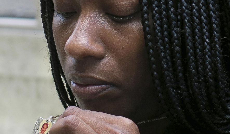 FILE - In this April 24, 2014 file photo, Tarshia Williams displays a pendant with her daughter, Talia's face on it outside of a federal courthouse in Honolulu. The U.S. government will pay Williams from Atlanta, $2 million for the Hawaii beating death of her 5-year-old daughter at the hands of a former soldier. The settlement amount was announced Tuesday, May 26, 2015, at a brief hearing in federal court in Honolulu. (AP Photo/Sam Eifling, File)