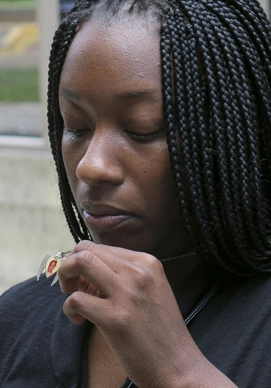 FILE - In this April 24, 2014 file photo, Tarshia Williams displays a pendant with her daughter, Talia's face on it outside of a federal courthouse in Honolulu. The U.S. government will pay Williams from Atlanta, $2 million for the Hawaii beating death of her 5-year-old daughter at the hands of a former soldier. The settlement amount was announced Tuesday, May 26, 2015, at a brief hearing in federal court in Honolulu. (AP Photo/Sam Eifling, File)