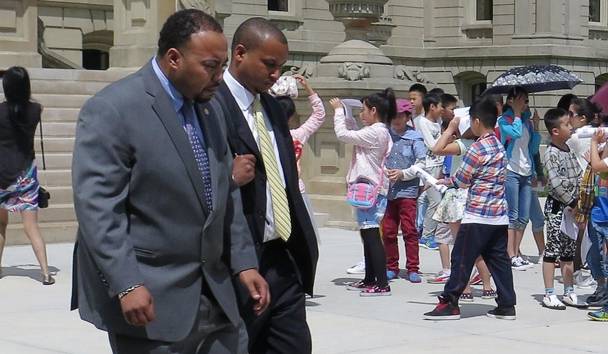 State Rep. Fred Durhal, left, escorts state Sen. Virgil Smith after a session at the State house in Lansing, Mich., Tuesday, May 26, 2015. Smith returned to work Tuesday, more than two weeks after being charged with three felonies in connection with a shooting incident at his home. The Detroit Democrat, who declined to answer questions from the media as he left the Senate chamber Tuesday, is facing the felonies and a misdemeanor in connection with a non-fatal shooting involving his ex-wife outside his Detroit home on May 10. (AP Photo/David Eggert)