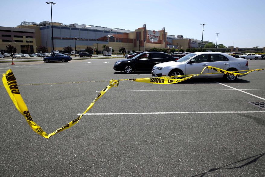 Crime scene tape blows in the wind near the scene of a fatal shooting in front of Resort World Casino in the borough of Queens in New York, Tuesday, May 26, 2015. The New York Police Department says a man suspected of killing his ex-girlfriend outside a casino has been shot to death by police. (AP Photo/Seth Wenig)