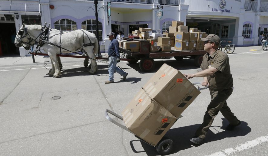 In a photo from Wednesday, May 6, 2015 in Mackinac Island Mich., United Parcel Service driver Dan Minta delivers packages on the island using a horse drawn cart. Horses do the heavy lifting on the island, hauling people and cargo across the car-free tourist destination in northern Michigan. Many of the 500 horses that are so vital to the island’s operations during the warm-weather months over winter on farms. (AP Photo/Carlos Osorio)